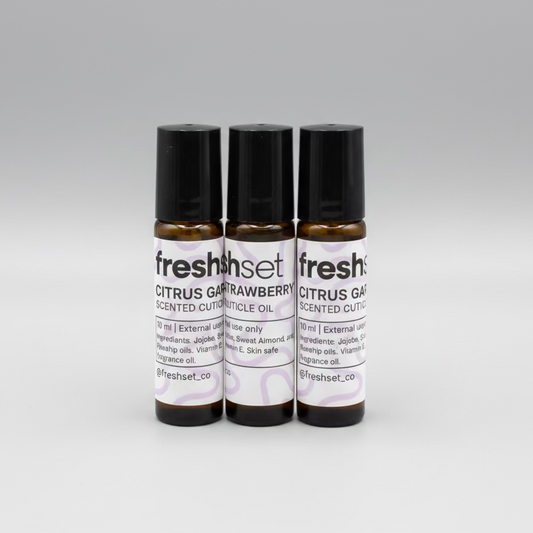 Three small bottles of cuticle oil on a dark gray background