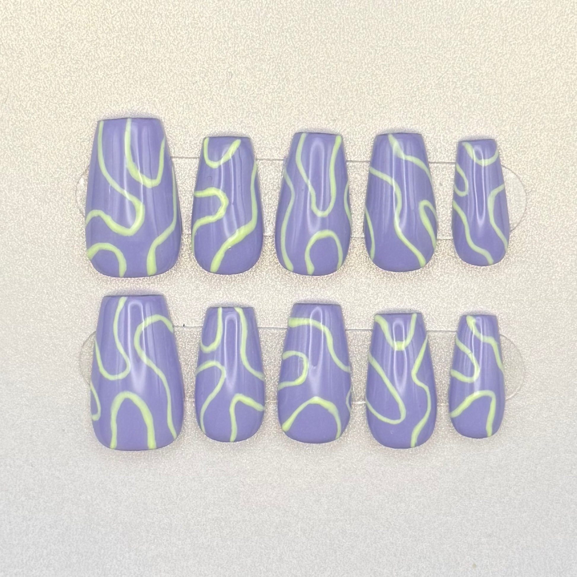Press on nails painted with lavender purple and light green swirls